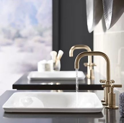 Kohler wading pool vessel sinks and brushed gold faucets on wall hung vanities