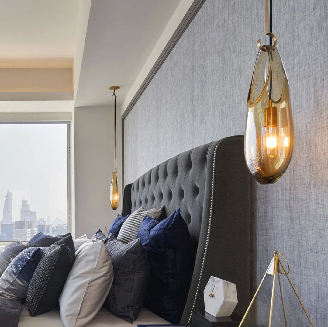 Hand blown glass pendant sconce in a modern gold smoked glass by sklo with a luxurious upholstered bed