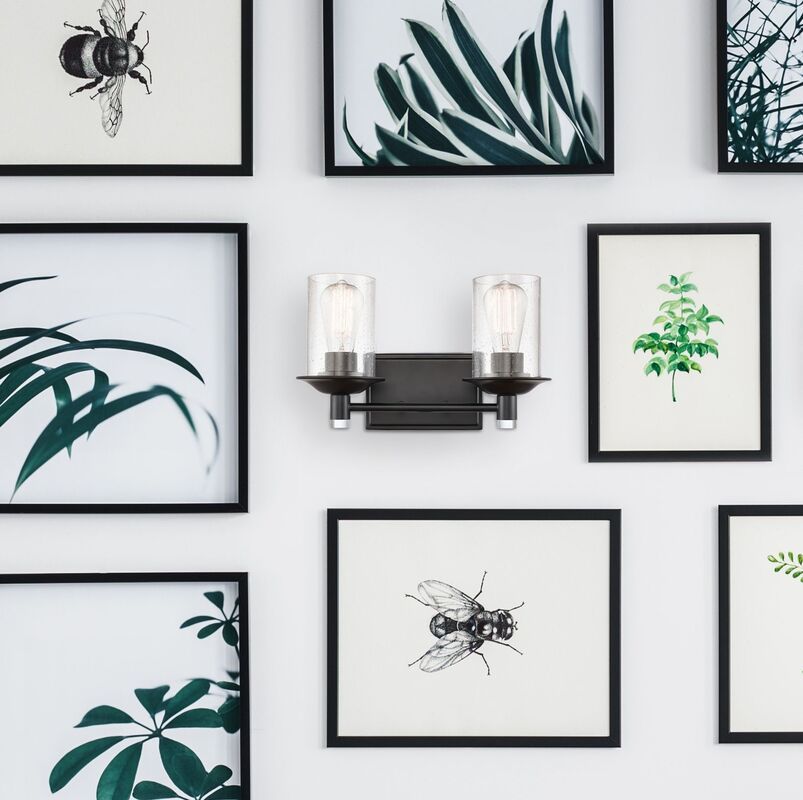 Matte black bathroom sconce with two lights and a black and white wall of pictures