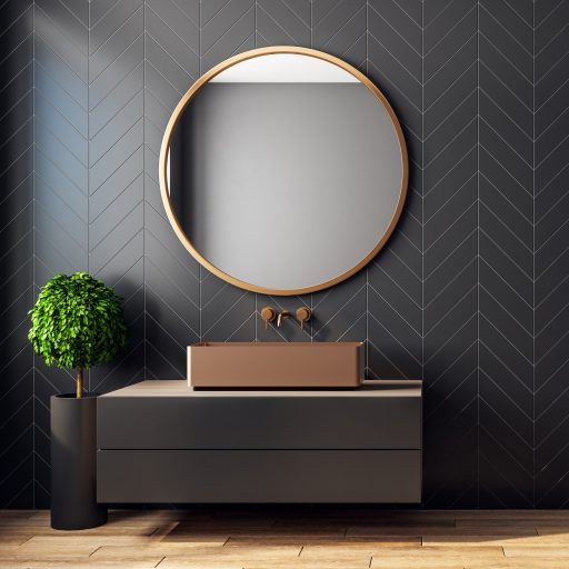 Bronze bathroom sink by zomodo with black and bronze wall mount faucet and round mirror mounted on a black chevron tile wall