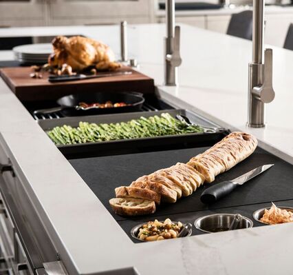 The Galley kitchen workstation sink with sliced baguette asparagus and more on fitted kitchen accessories in a quartz countertop and stainless steel kitchen faucets