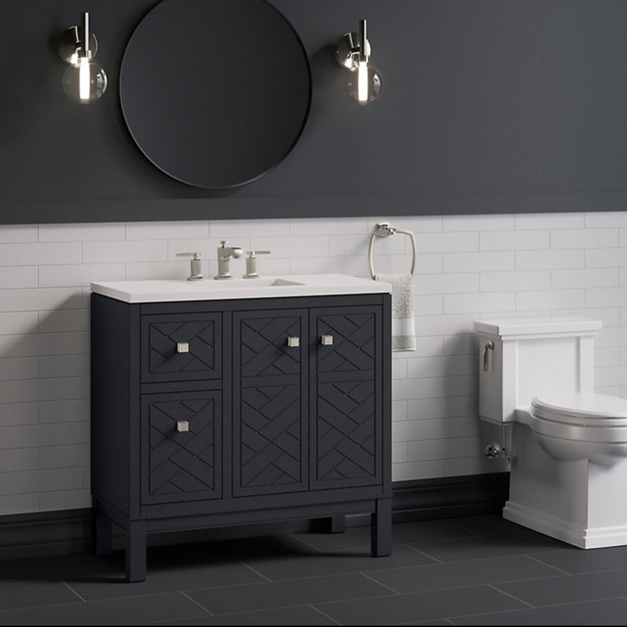Kohler Bauxline vanity in dark grey with subway tile and margaux faucet and polished nickel wall sconces with a matte black round Kohler mirror 
