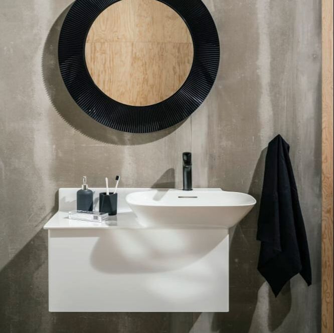 Matte white wall hung vanity by Laufen from their Ino series with a matte black faucet and concrete walls