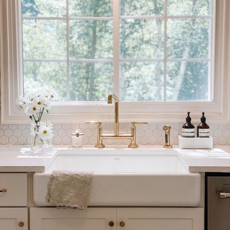 Kallista gold brass bridge faucet and white farmhouse sink with white quartz counterop 