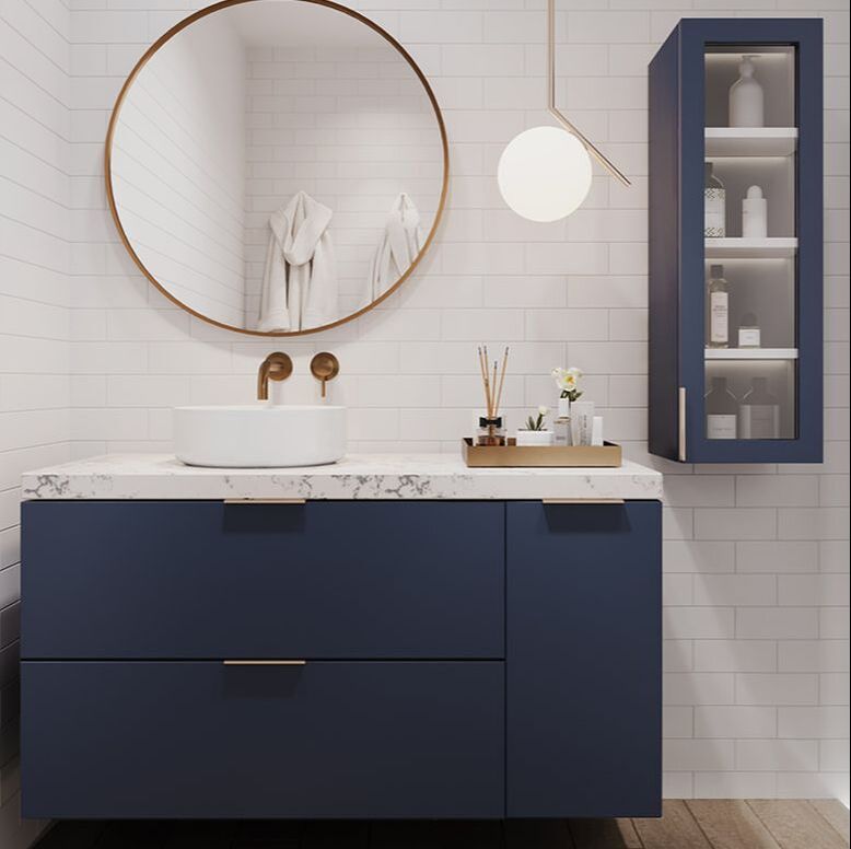 DM Bath Navy Blue vanity with gold hardware and a matte white vessel sink champagne bronze wall mount faucet round mirror and bath accessories on the quartz countertop