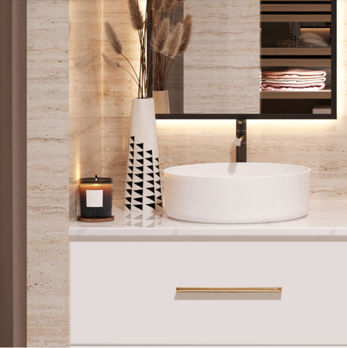 Matte white vessel sink on a white floating vanity with gold hardarwe in a warm travertine stone bathroom with a candle burning
