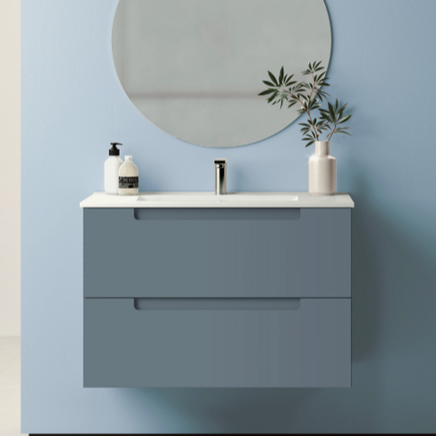 Ico wallhung vanity in steel blue with slab front drawers and integrate pulls a white seamless one-piece countertop and chrome faucet below a round mirror in a blue bathroom