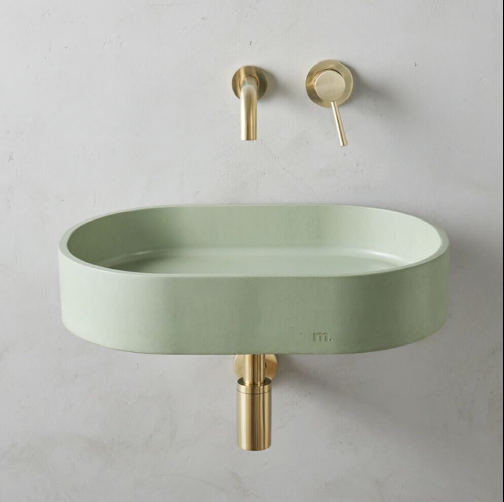Mudd concrete wall mount bathroom sink with brushed gold wall-mount faucet on a concrete wall