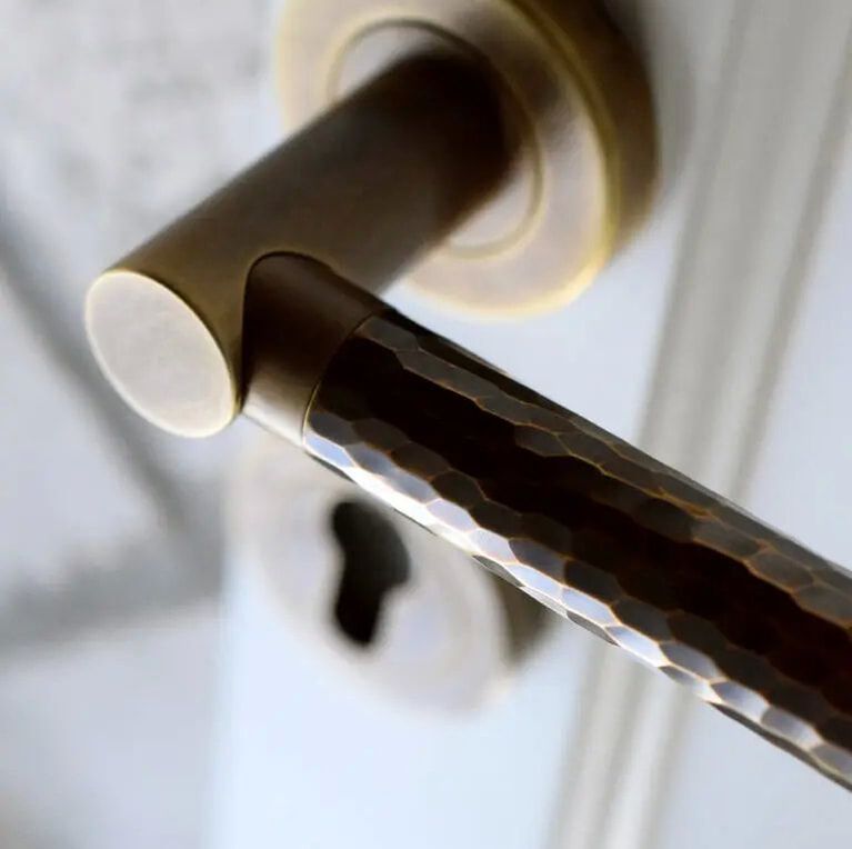 Turnstyle designs hammered brass door hardware lever on white door